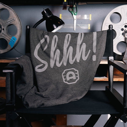 Alamo Drafthouse SHHHHHH! Sweatshirt Blanket draped over a director's chair