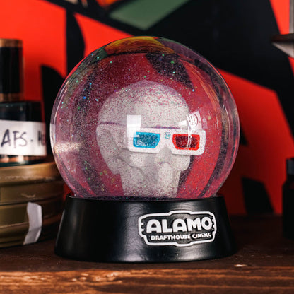 Alamo Drafthouse 3D Skull Snow Globe sitting on a wooden table